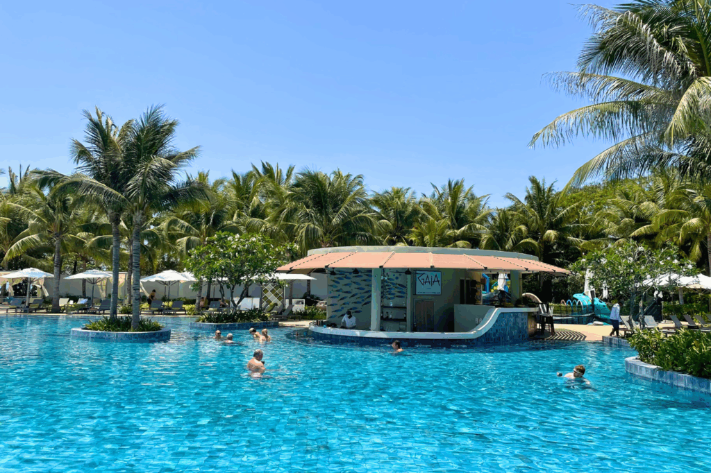 People enjoying the swimming pool and swim-up pool bar at Melia Ho Tram Beach Resort, Vietnam