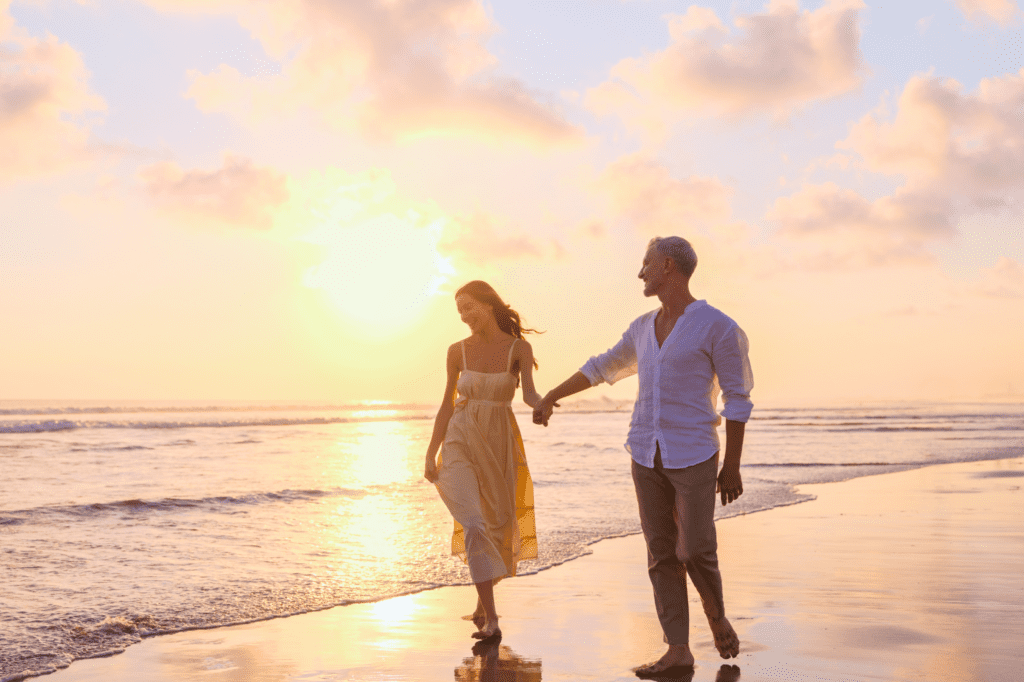 A couple walking along Seminyak beach at sunset.