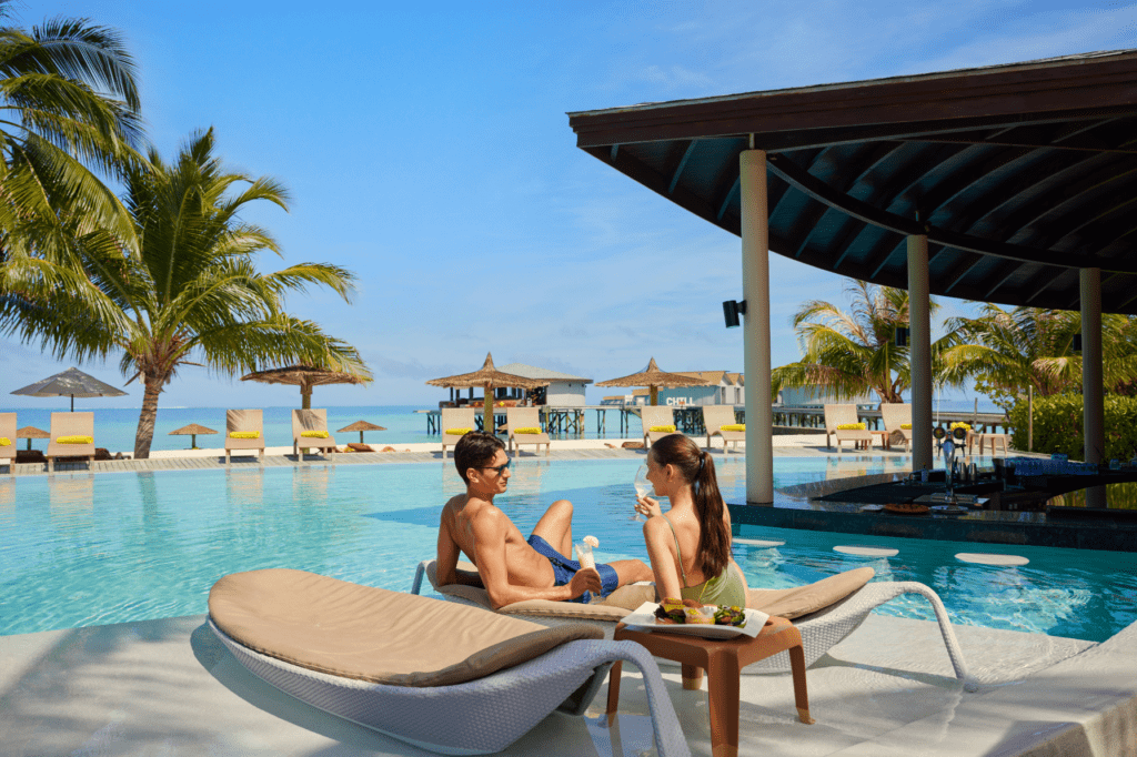 A couple relaxing poolside at Centara Ras Fushi Resort & Spa