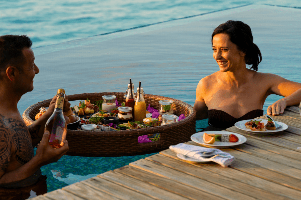 A couple enjoying a floating breakfast in their private pool at Outrigger Maldives Maafushivaru Resort