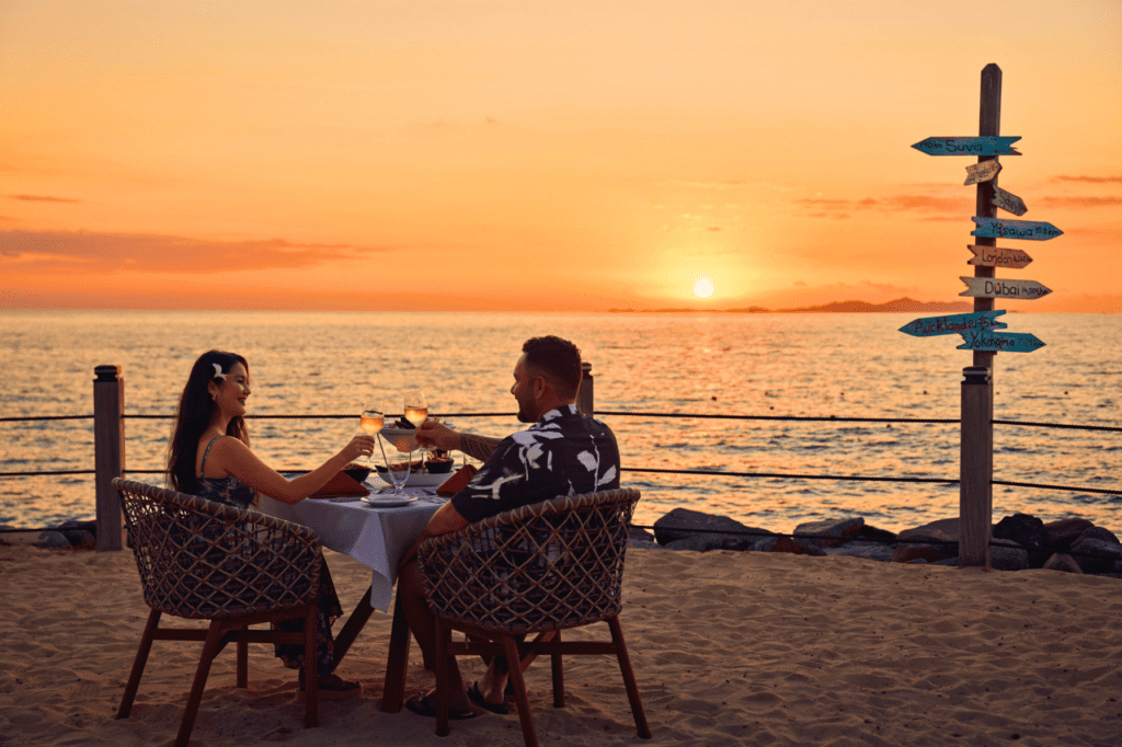 A couple enjoying dinner and drinks oceanside in Denarau.