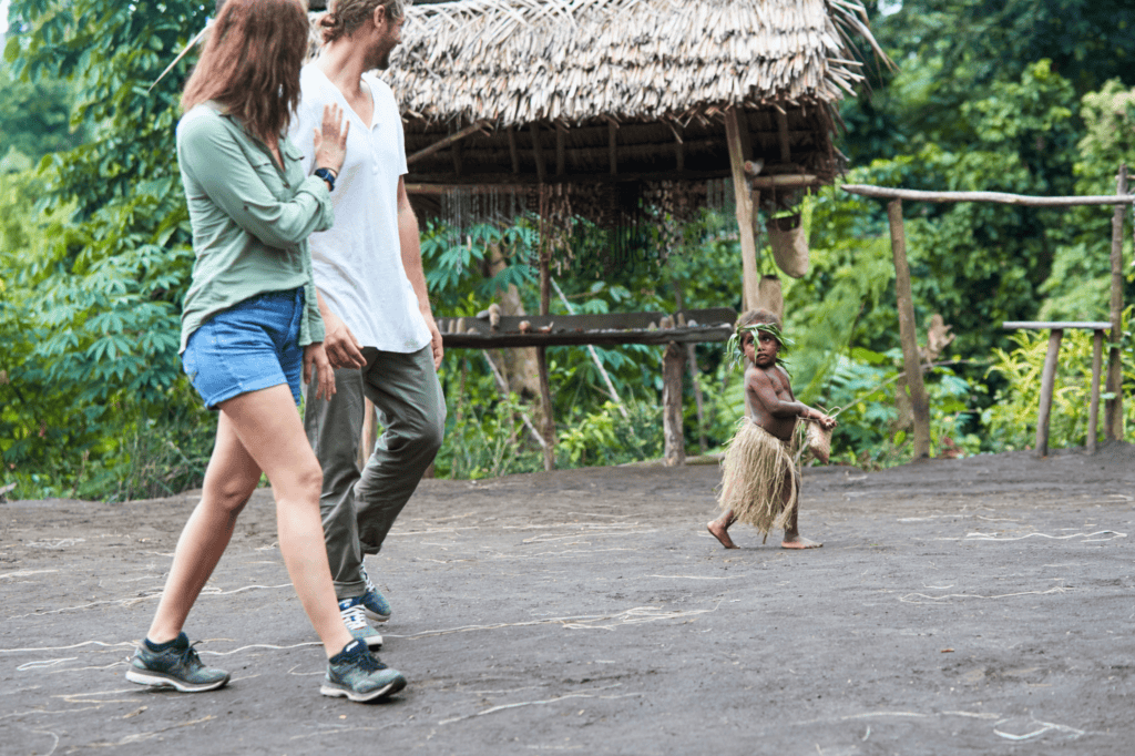 A couple greeting a young child dressed in traditional costume at Imaio Cultural Village, Tanna Island, Vanuatu
